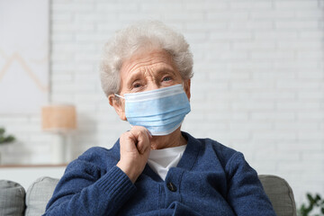 Elderly woman in medical mask in living room