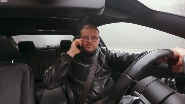 In-car shot of a man holding a phone to his ear while driving, highlighting distracted driving, road safety risks, and unsafe behavior behind the wheel.
