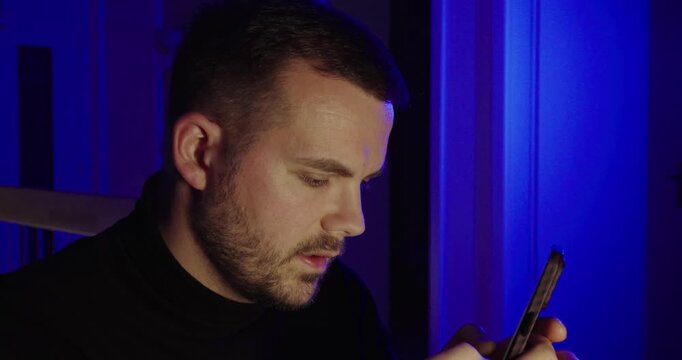 Cinematic close-up of a man typing on his phone while speaking the words he writes&mdash;ideal for voice dictation, handsfree messaging, content creation, and modern communication in blue ambient light.