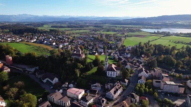 Aerial of a beautiful town in Switzerland with a lake and alps in the background, Uster