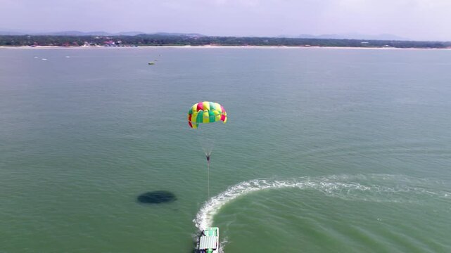 Tourist riding speed boat Parasailing on Arabian Sea in background colva beach at south goa, india. day time, circle shot, drone shot, 4k.