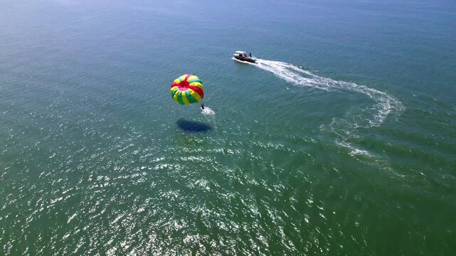 Speed boat parasailing dip on Arabian Sea with waves and foam at goa. day time, stable shot, drone shot, 4k.