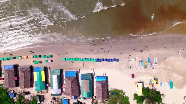Two tone sea water of colva beach shoreline with tourist, shacks and sunbeds at goa. day time, bird eye view, push back shot, drone shot, 4k.