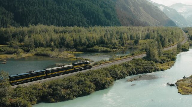 Medium aerial tracking shot of the Alaska railroad as it makes its way to Whittier Alaska.