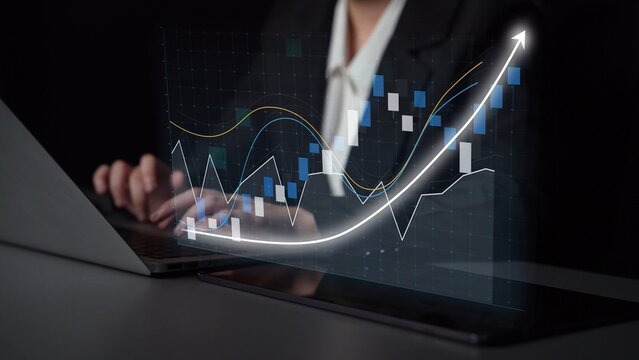A business professional analyzes financial data using a laptop, with dynamic charts illustrating growth trends and market fluctuations in a contemporary workspace. Copula - Powered by Adobe