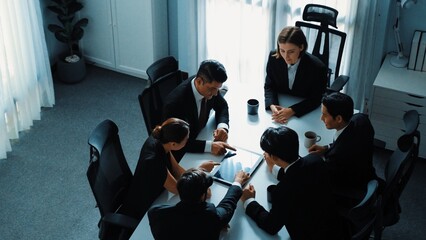 Top view of diverse business team discuss about marketing idea while businessman analyze financial graph from tablet at meeting room. Group of smart team brainstorm idea at conference. Directorate.