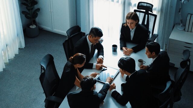 Top view of diverse business team discuss about marketing idea while businessman analyze financial graph from tablet at meeting room. Group of smart team brainstorm idea at conference. Directorate. - Powered by Adobe