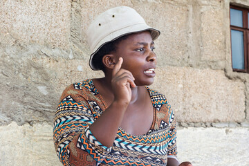 village african woman portrait, pointing finger gesturing outdoors in the nature ,at home wall behind