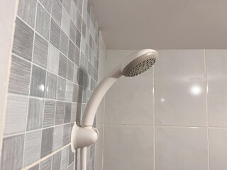 a white handheld shower head mounted on a wall bracket inside a bathroom.