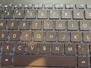 Close-up of a modern backlit laptop keyboard with black chiclet keys.