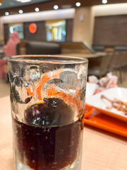low-angle shot of a half-filled dimpled glass mug containing a dark carbonated soft drink (cola) with visible condensation and bubbles.