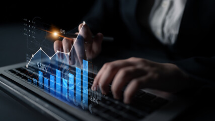 A business professional engages with financial analysis, showcasing digital graphs and statistics on a laptop in a sophisticated dark office setting. Scalp