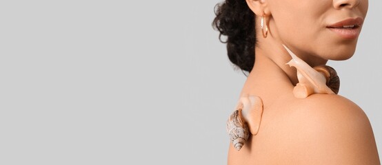 Young African-American woman with giant Achatina snails on light background with space for text, closeup © Pixel-Shot