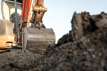 Obraz premium An excavator or backhoe machinery part with soil ground in construction activity. Building industrial scene, close-up and selective focus.