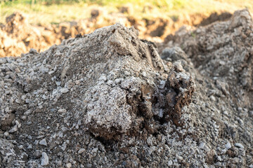 Fototapeta premium Soil bulk at that excavated at construction building site. Industrial working place, close-up and selective focus.