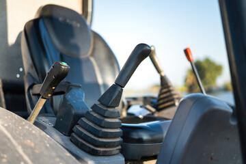 Close-up at backhoe or excavator machine controlling handle at the driver cabin, it using to operate the machine. Industrial equipment object, selective focus.