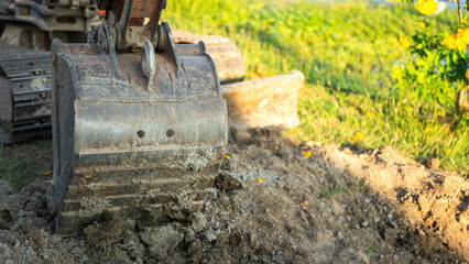 An excavator or backhoe machinery part with soil ground in construction activity. Building industrial scene, close-up and selective focus.