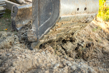 An excavator or backhoe machinery part with soil ground in construction activity. Building...