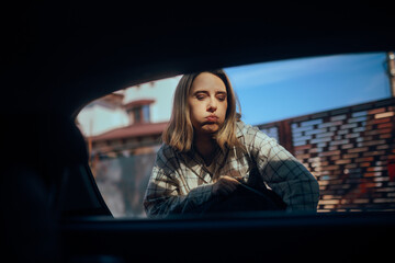 Exhausted Woman Puts Luggage in Trunk and Prepares for Travel. Tired lady packing up to leave in a car trip
