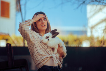 Exasperated Woman Holds a Large House Rabbit. Stressed pet owner not knowing how to take care of it