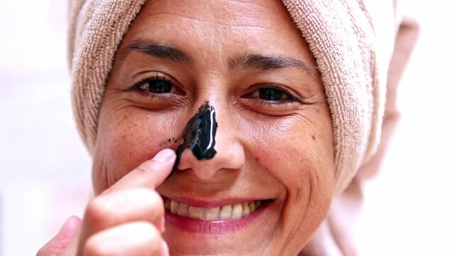 Mature woman applying a purifying black nose mask