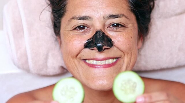 Woman applying beauty mask and cucumber slices on her face