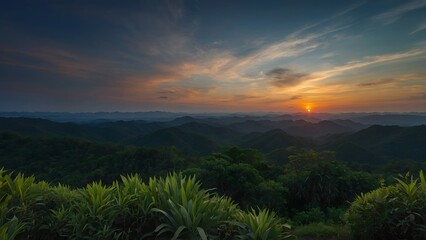 Panoramic nature view of a golden sunrise and sunset over misty mountain peaks where clouds float above a forest valley at dawn and dusk