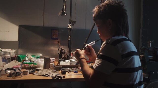 The girl works on a jewelry in the workshop