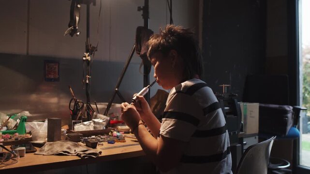 The girl works on a jewelry in the workshop