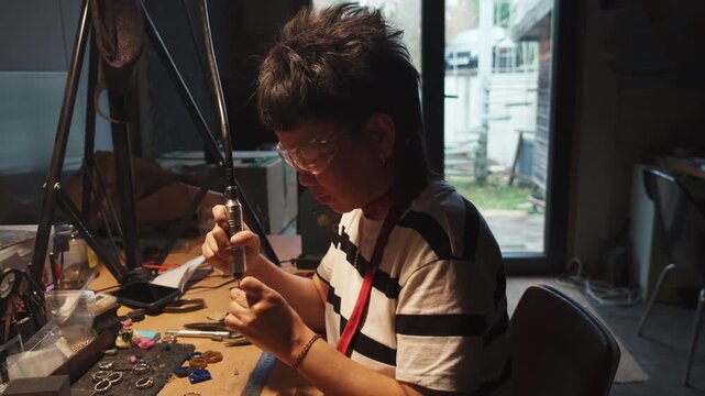 The girl works on a jewelry in the workshop