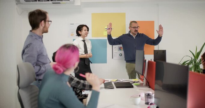 Business team discusses project ideas in an office setting with both men and women present during a group meeting at midday
