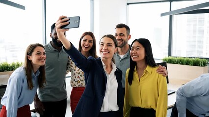 Group of business colleagues takes a selfie in office, smiling, blurred background