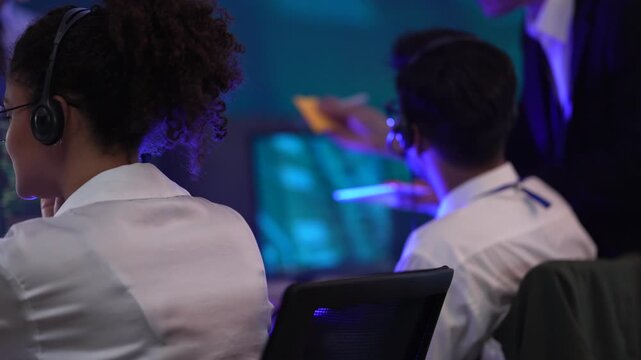 Professional technical support team managing customer service in a high-tech data center. Operators handling client communications and troubleshooting issues using digital interfaces during a night sh