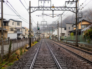 雨が降る住宅街を通る能勢電鉄妙見線の線路