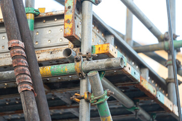 Close-up at metal pipe connection joint of the working platform scaffold at the construction work site. Industrial equipment and object, selective focus.