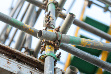 Close-up at metal pipe connection joint of the working platform scaffold at the construction work site. Industrial equipment and object, selective focus.
