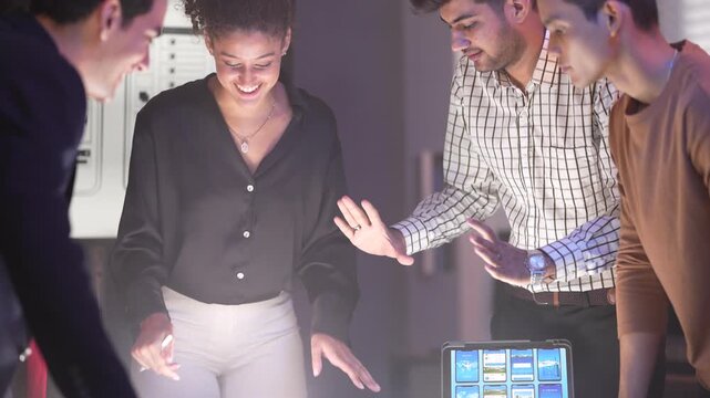 A smiling woman with curly hair discussing mobile app wireframes on a large presentation screen with a male colleague holding a laptop. The screen displays sketches for "Front-End Developer Expert" an