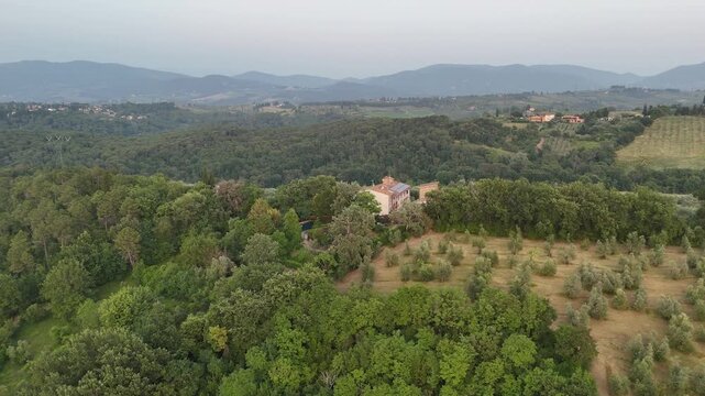 Aerial views of houses on a hill in Impruneta near Florence, Italy, featuring the rolling hills of the scenic Tuscan landscape. As the sun is setting on a beautiful summers day.