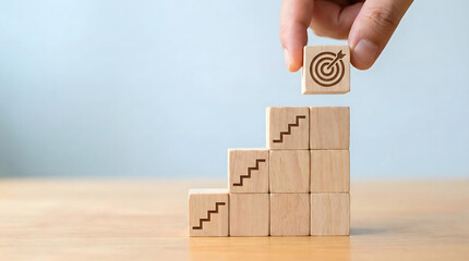 Hand placing wooden block with target icon on top of stacking steps,business goal achievement and career ladder climbing concept,strategy for success and development,leadership vision and ambition