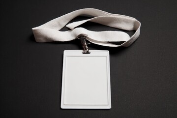 A pristine, blank white identification badge holder is presented with a matching white fabric lanyard, set against a dark, minimalist background. The empty plastic card allows for customizable content