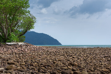 Rocks/stones on the  beach during a daylight on the islands, Thailand.Background image of the beach with sea in the distance with pebble stones.