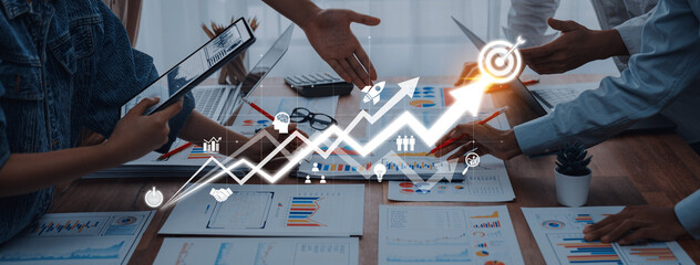 A dynamic business meeting showcasing professionals collaborating on financial growth and strategy, utilizing charts, laptops, and teamwork for effective outcomes. Trope