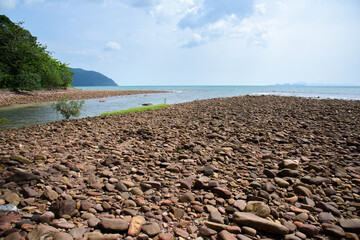 Rocks/stones on the  beach during a daylight on the islands, Thailand.Background image of the beach with sea in the distance with pebble stones.