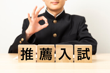 「推薦入試」と書かれたブロックとガッツポーズをする男子学生