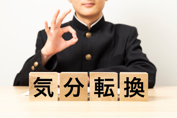 「気分転換」と書かれたブロックとOKサインをする男子学生