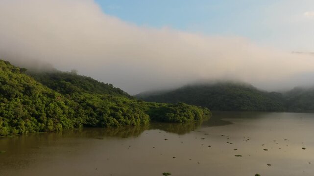 Misty Forested Hills Surrounding Brownish Lake At Presa El Carrizo In Jalisco, Mexico. ascendiing drone approach