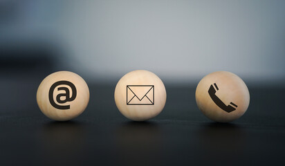 Wooden blocks display email, at symbol, and phone icons, representing various contact methods for customer service and communication 
