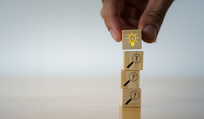 Solution, problem solving concept. Wooden blocks with a lightbulb and question mark magnifiers icons, symbolizing inquiry leading to insight and problem solving.