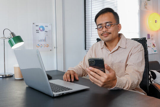 Young man with laptop and mobile phone at desk working on start up business in open plan office 
