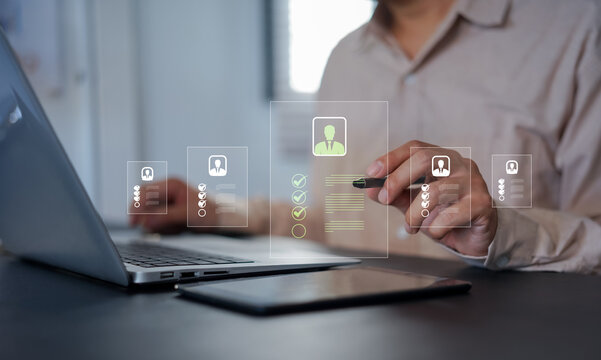 Businessman using magnifying glass to analyze resumes and select qualified candidates on a virtual interface, representing modern recruitment, HR analytics, and digital hiring process.